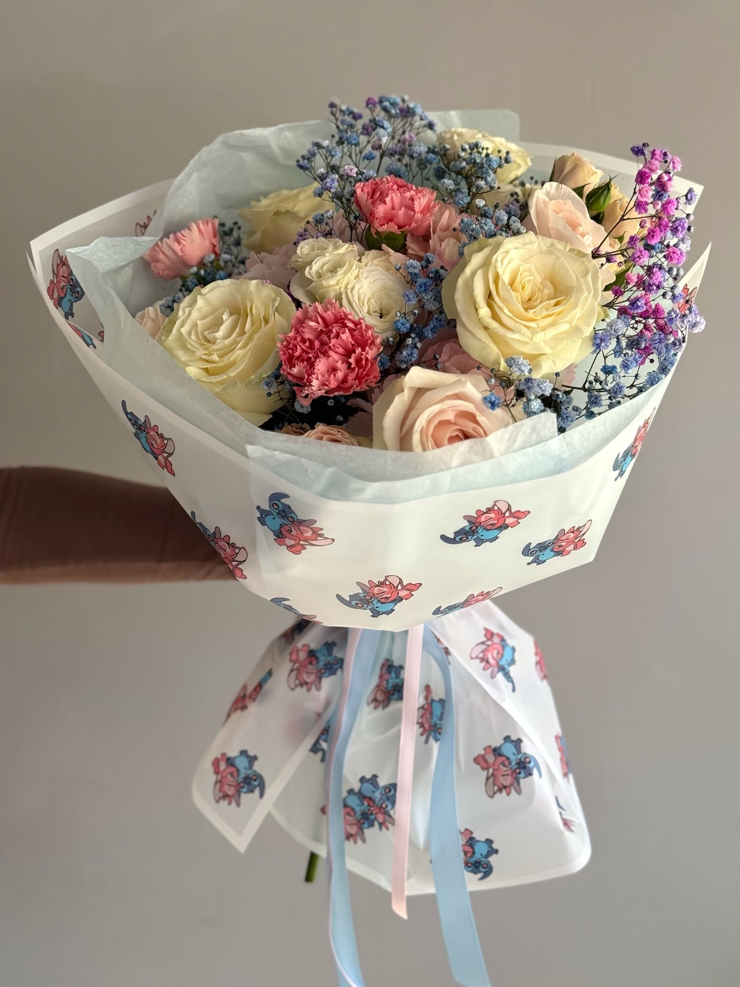 Bouquet of flowers held by a person against a plain background