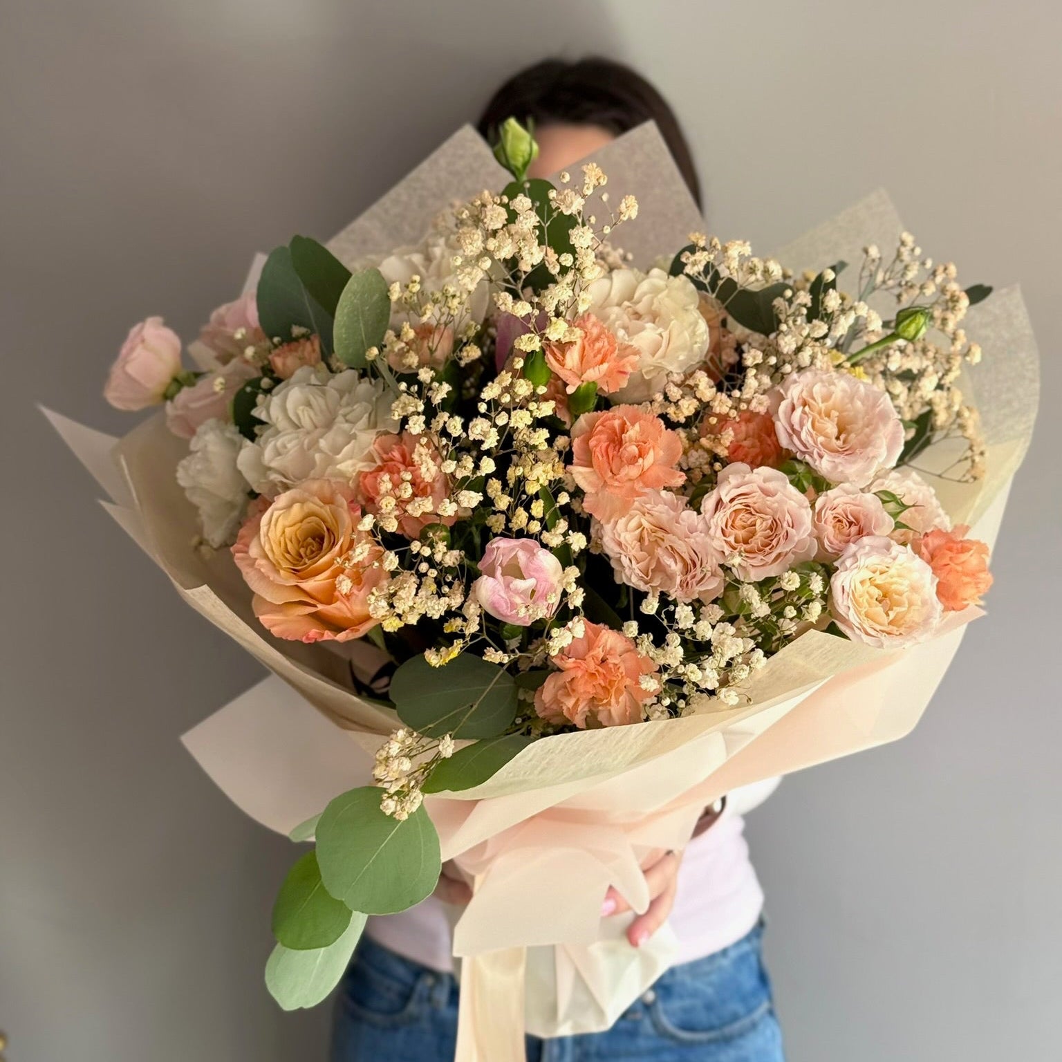 Person holding a bouquet of flowers against a plain background