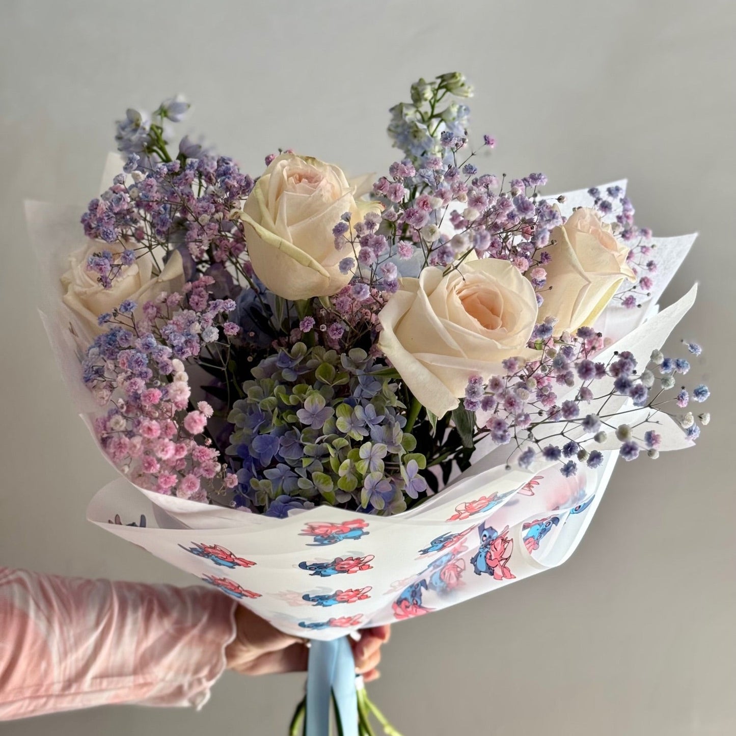 Bouquet of flowers held by a person against a plain background