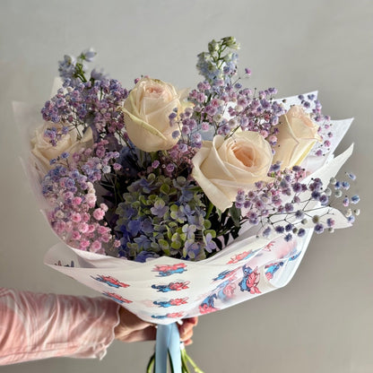 Bouquet of flowers held by a person against a plain background