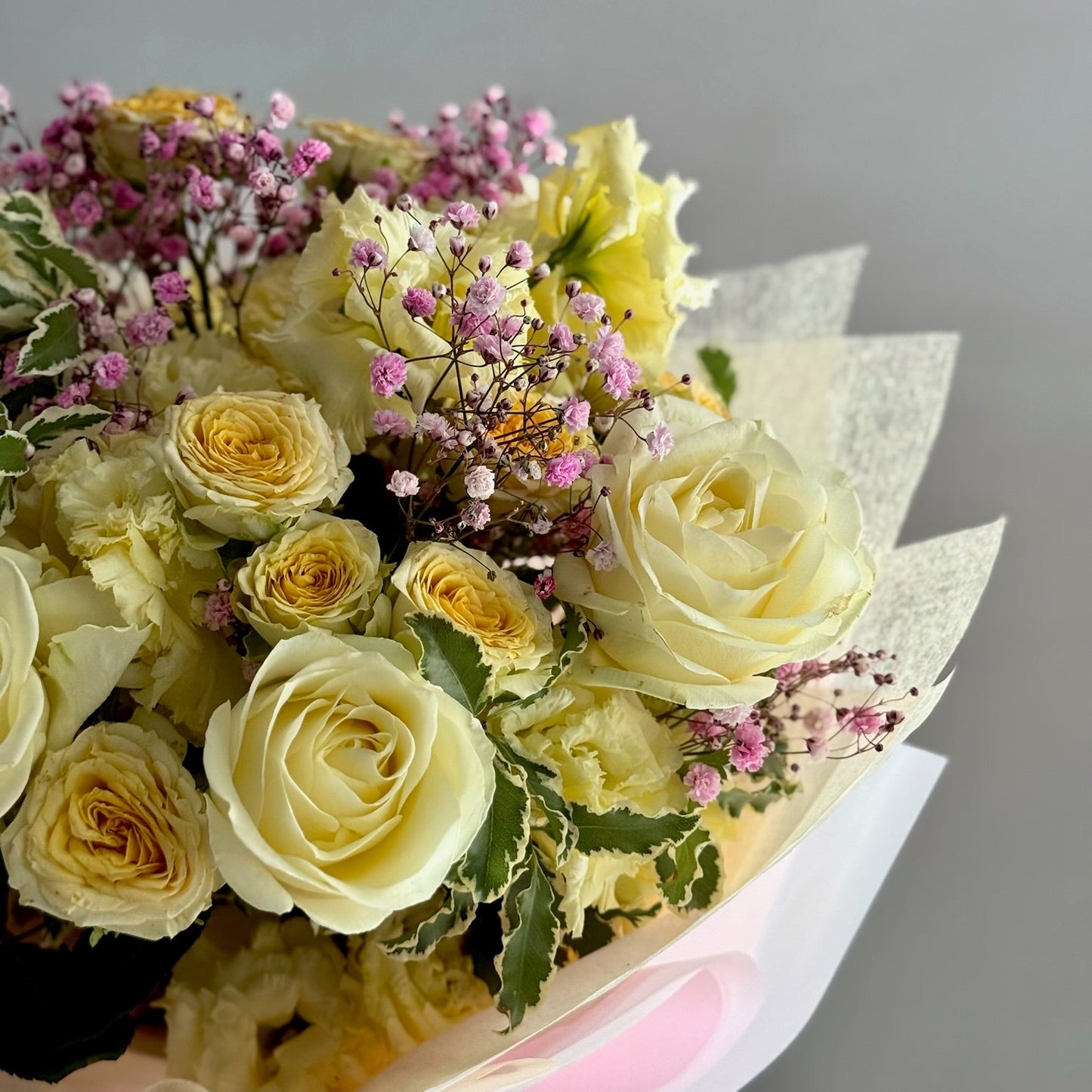 Bouquet of yellow roses and pink flowers on a gray background