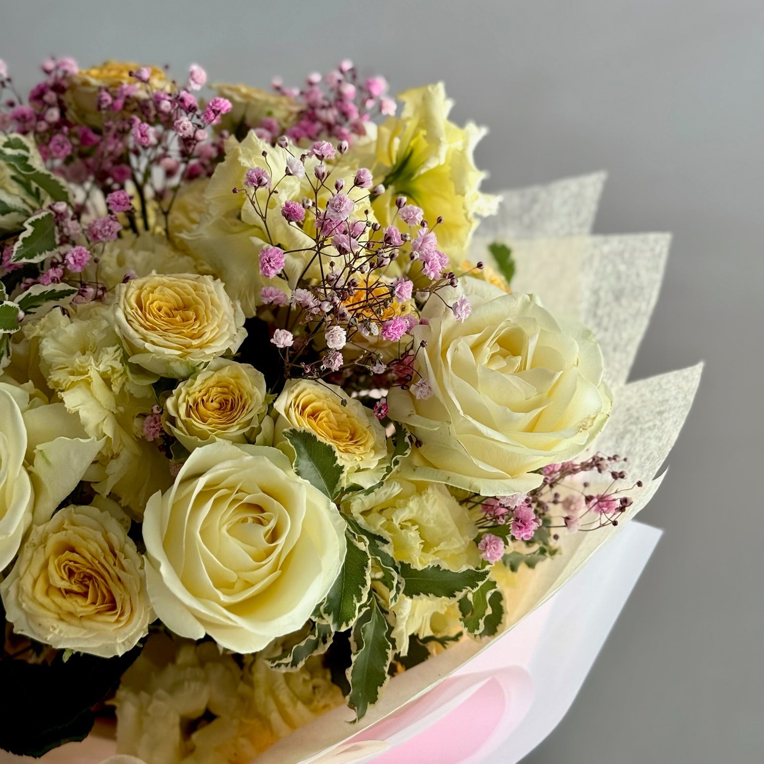 Bouquet of yellow roses and pink flowers on a gray background