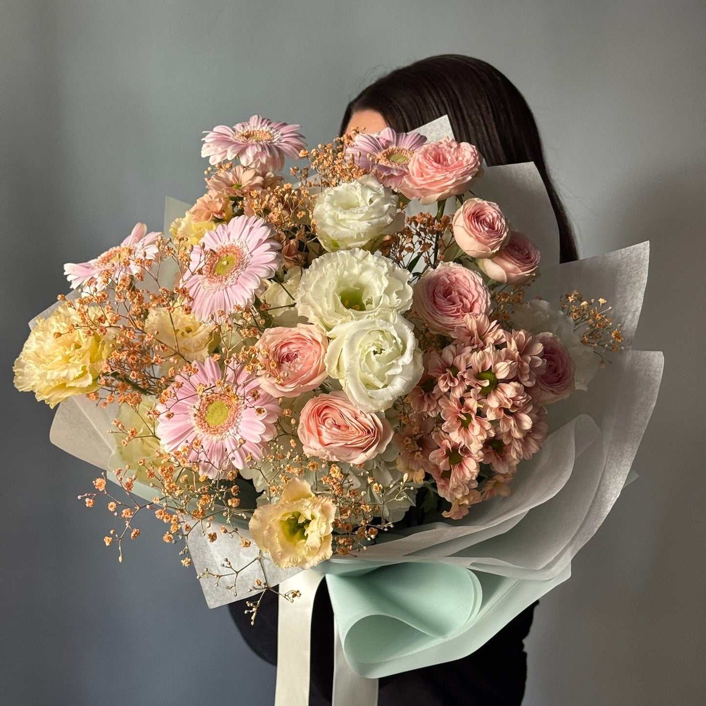 Person holdin large bouquet with white and pink flowers