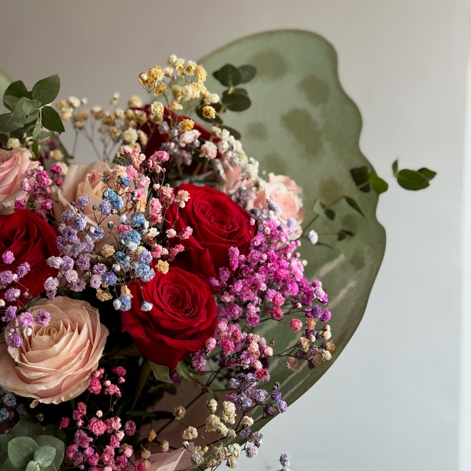Bouquet of colorful flowers with red roses and pink roses on a light background