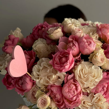 Bouquet of pink and white flowers with a pink heart-shaped card on a gray background