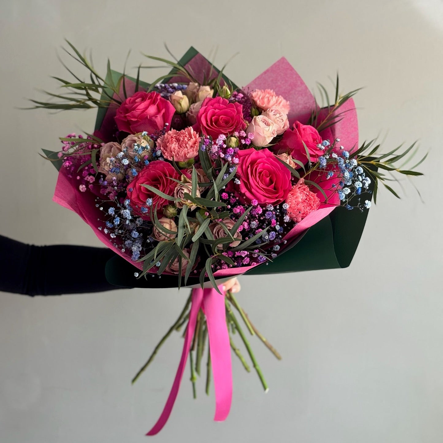 Bouquet pink flowers held by person on grey background 