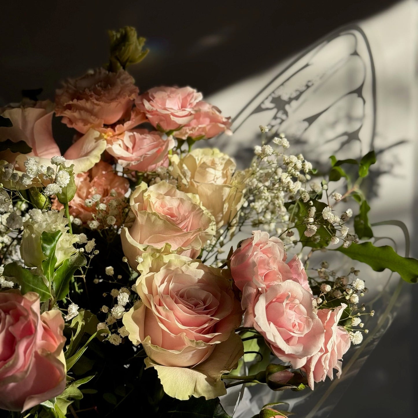 Bouquet of pink and white flowers with green leaves on a dark background