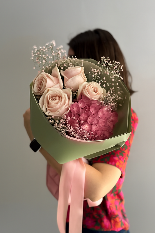 Person holding a bouquet of flowers with a plain background