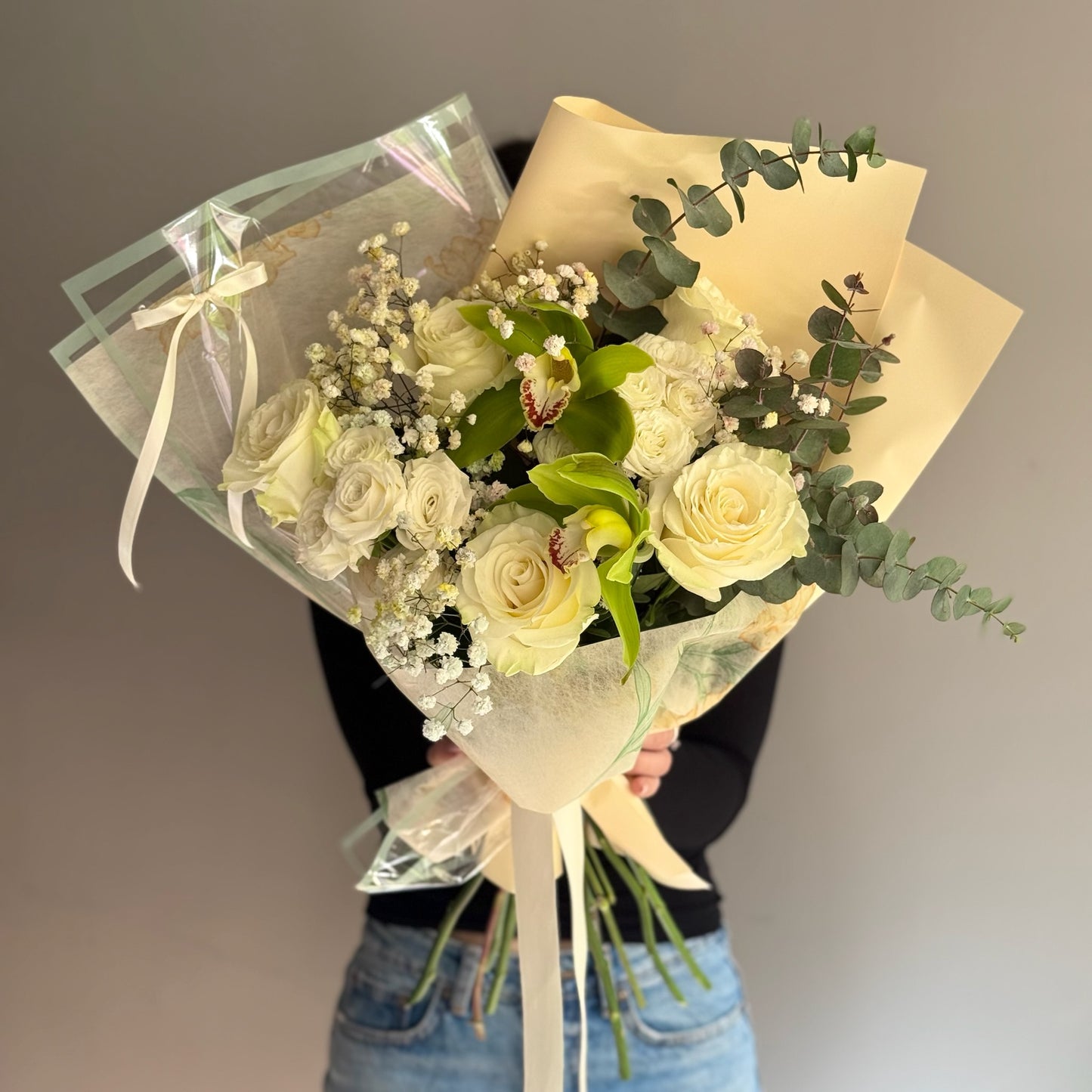 Bouquet of yellow roses held by a person against a blurred background.