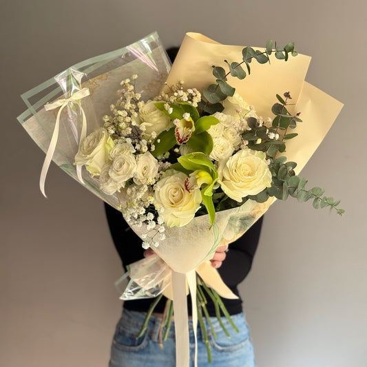 Bouquet of yellow roses held by a person against a blurred background.