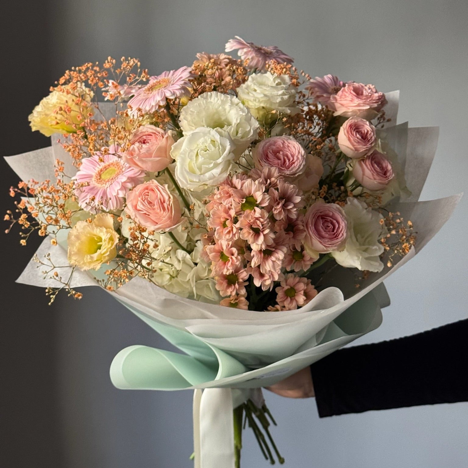 Large bouquet held against grey background 