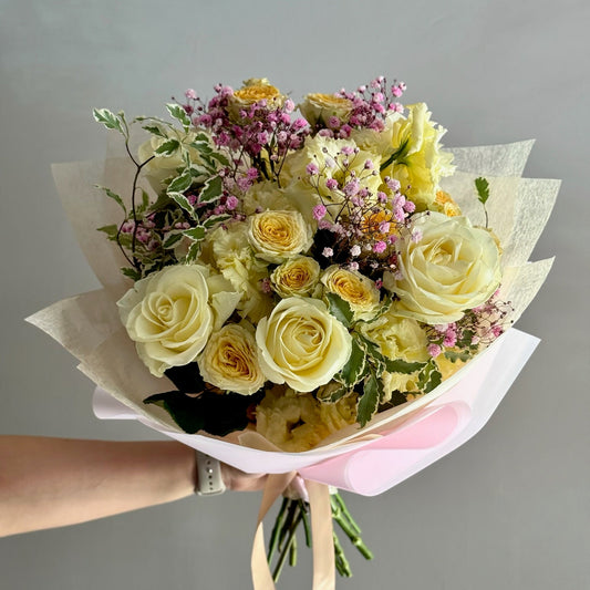Bouquet of flowers held by a person against a gray background