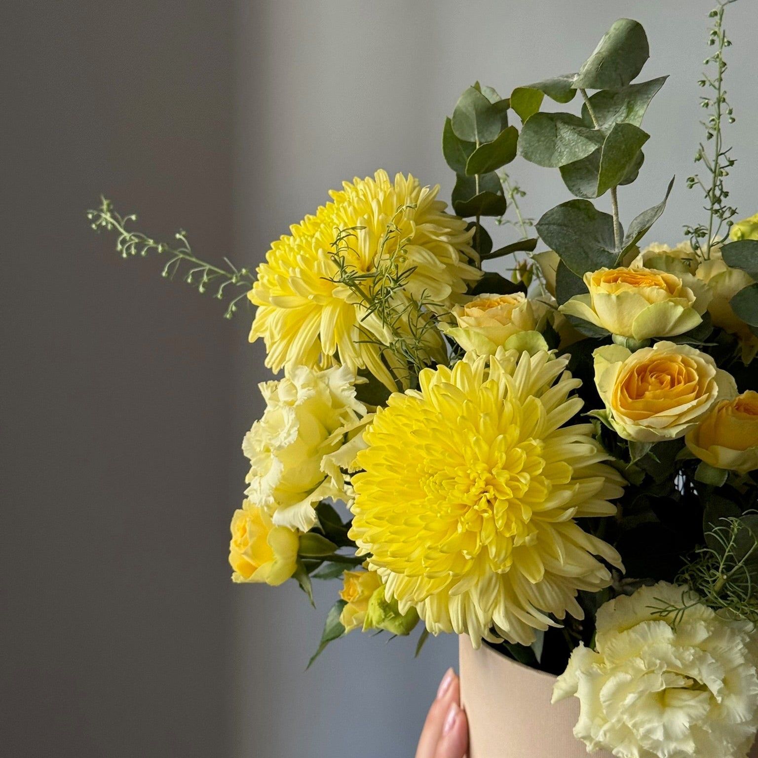 Bouquet of yellow flowers in a vase against a gray background
