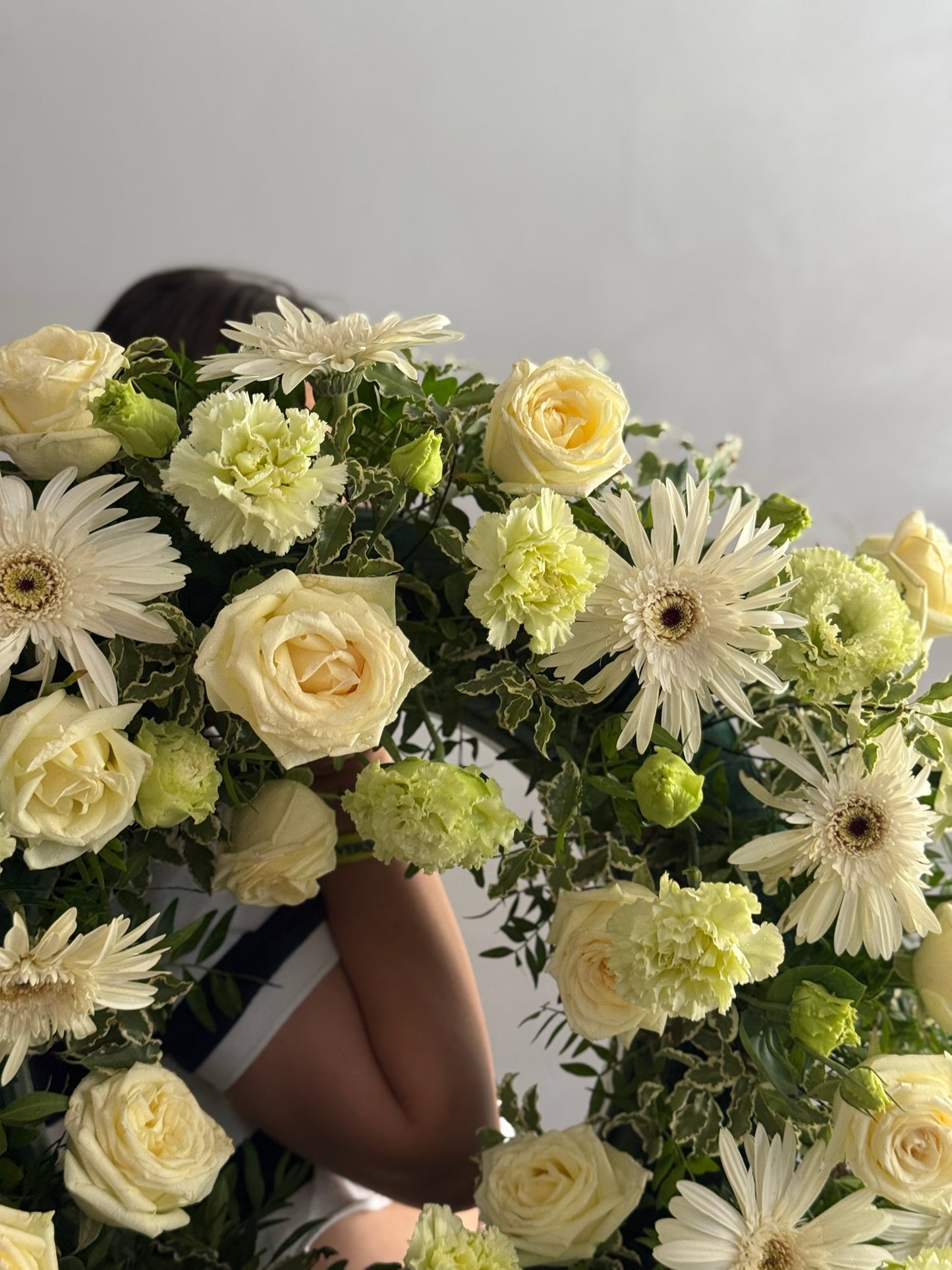 Person partially hidden by a large bouquet of flowers with white and yellow flowers.
