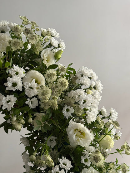Bouquet of white flowers with greenery on a light gray background