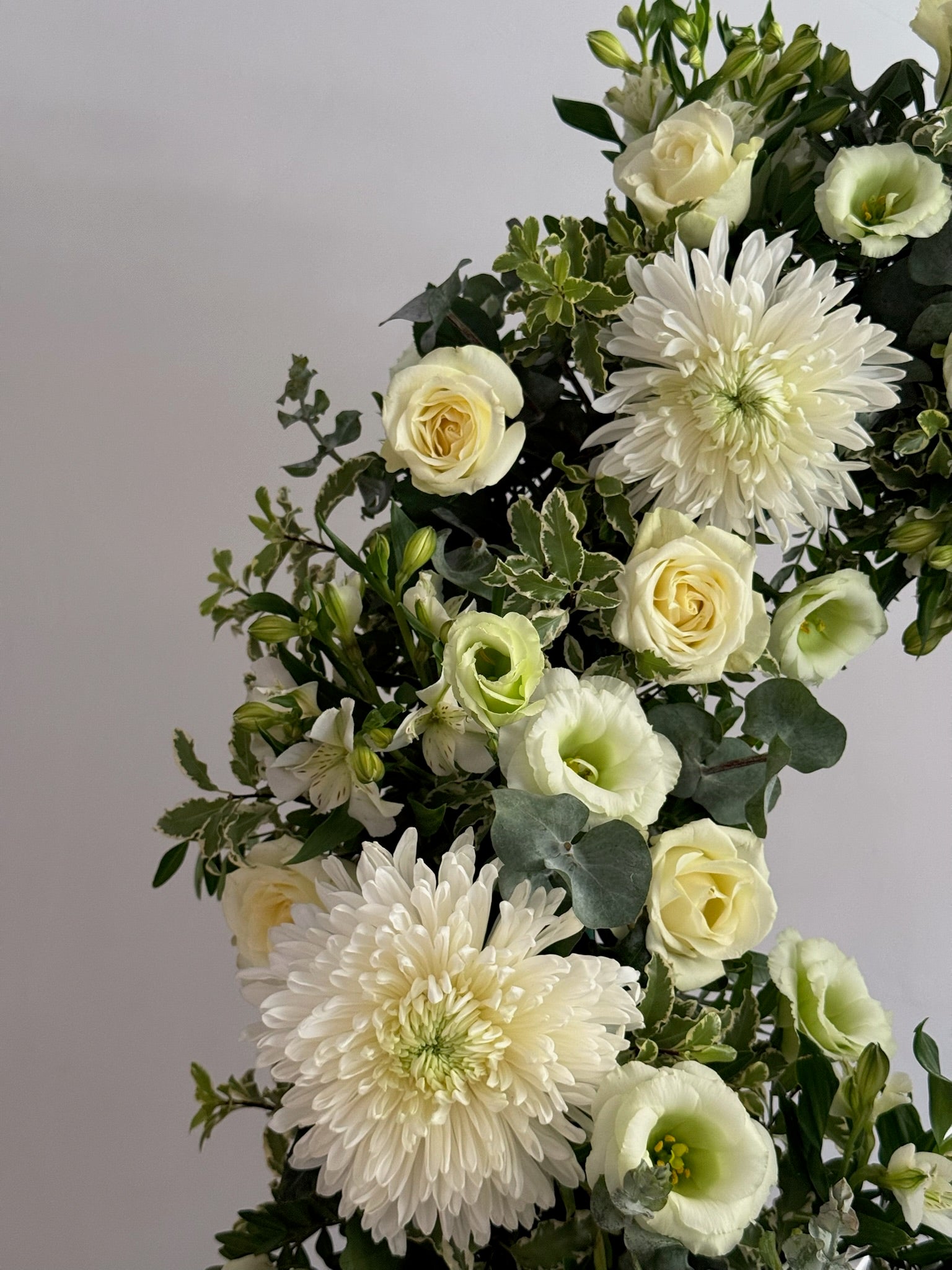 Bouquet of white and light green flowers with green leaves on a gray background