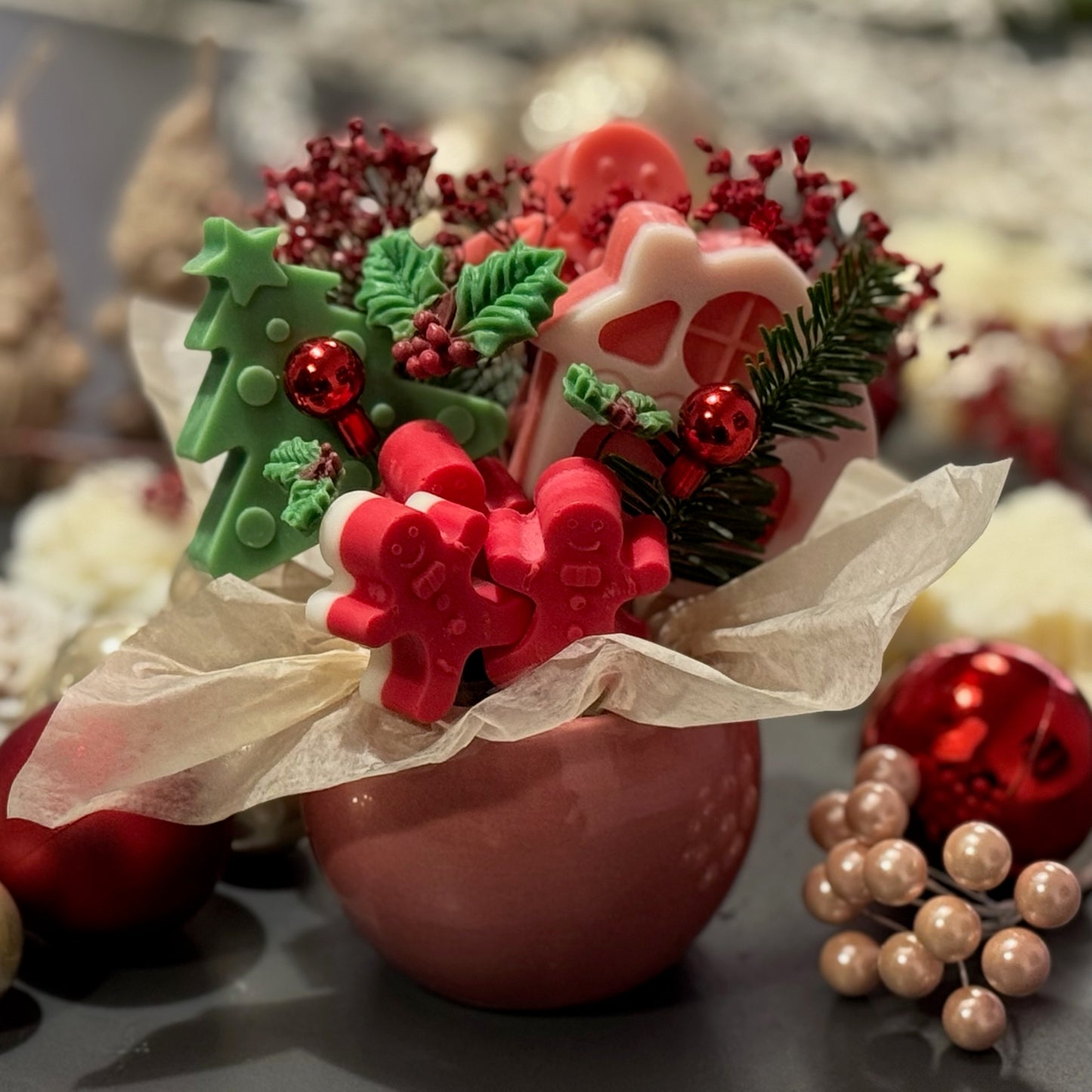 Decorative Christmas arrangement with gingerbread cookies, holly, and berries in a pink vase.