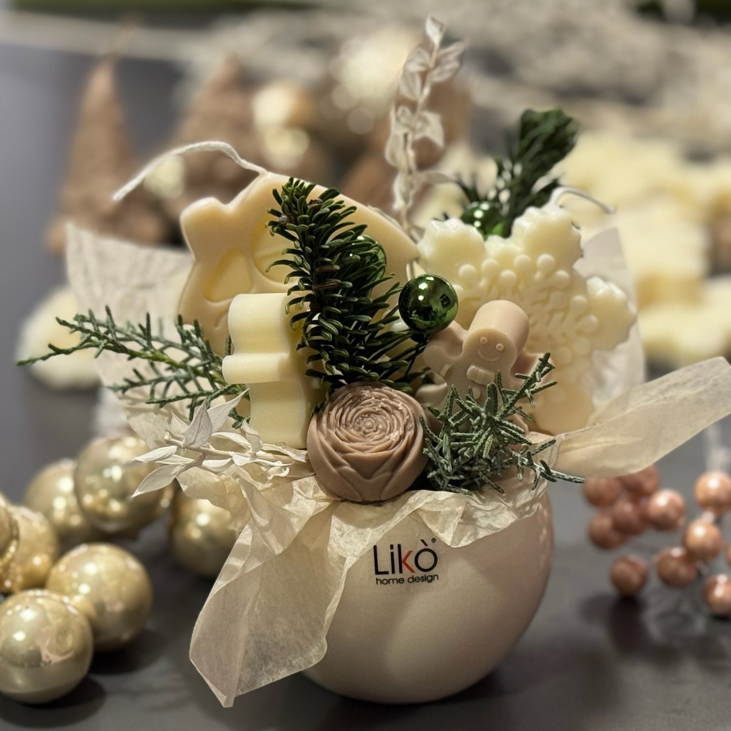 Decorative arrangement with white flowers, greenery, and a 'Liko' branded vase on a blurred background.