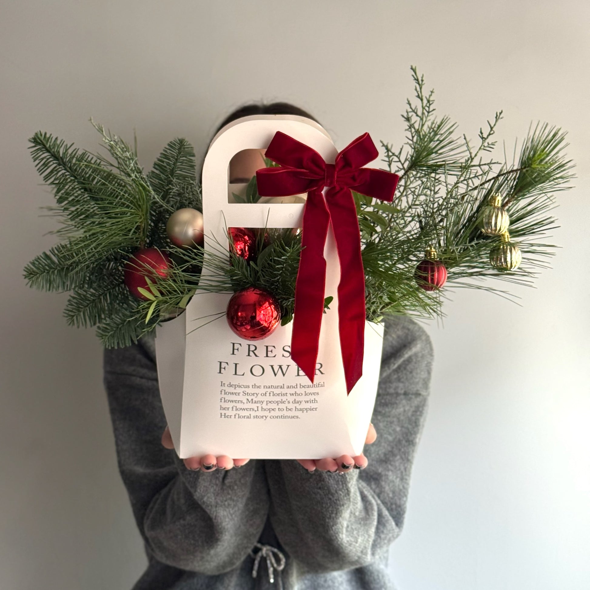 Aranjament Winter Red Glow în pungă cu mix de conifere, globuri roșii și fundă festivă