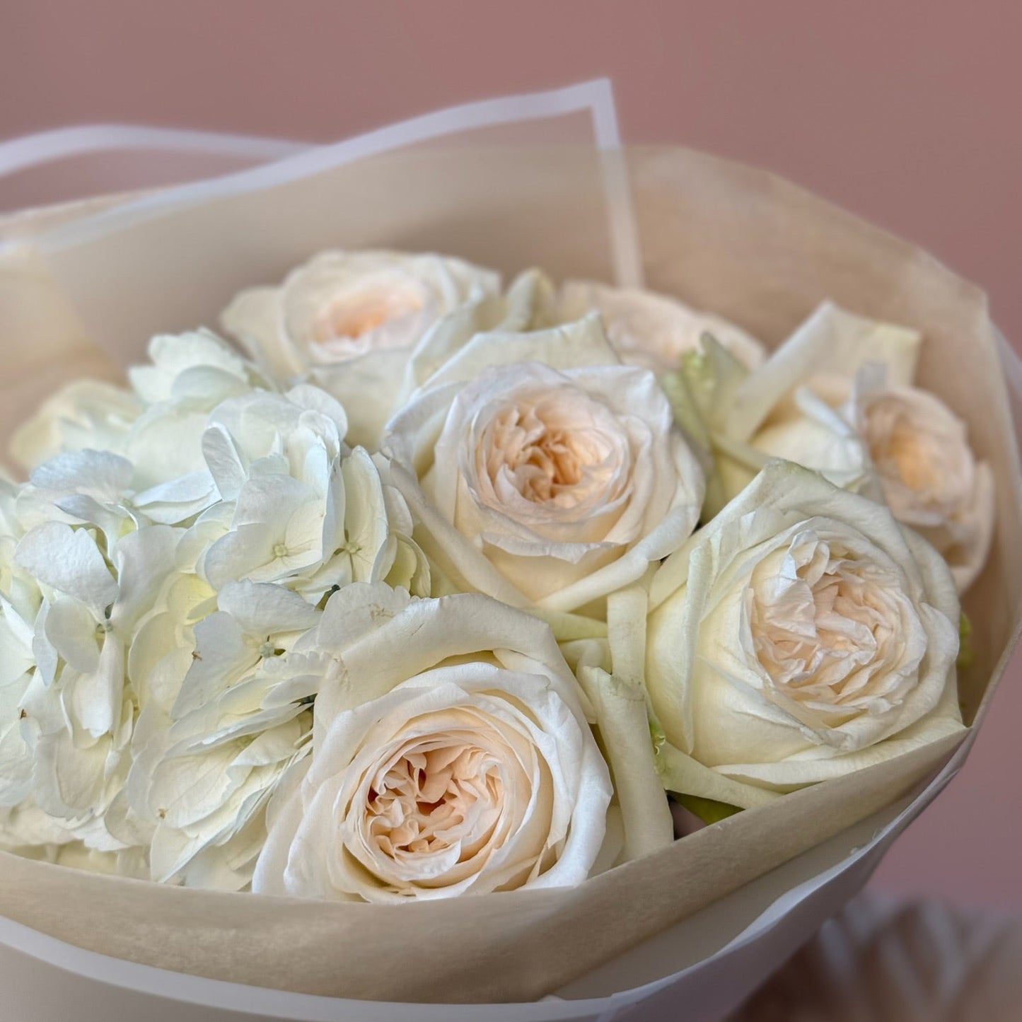 Bouquet of white and light pink roses in a box with a soft pink background