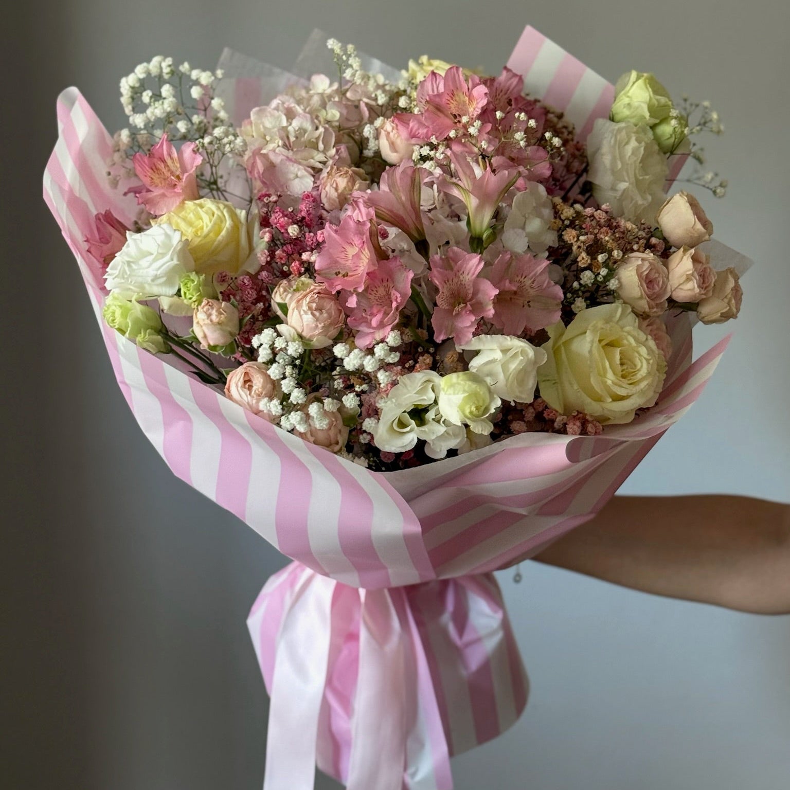 Buchet elegant cu trandafiri și hortensie în nuanțe de alb și roz, cu ambalaj roz cu dungi