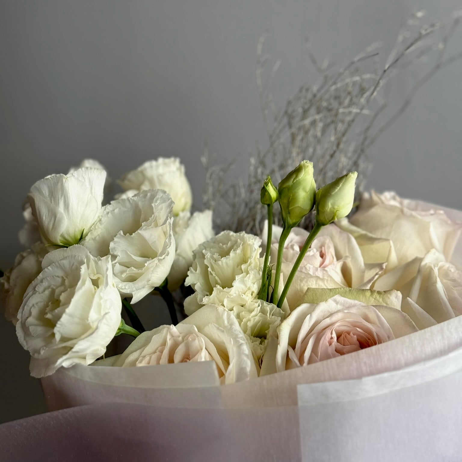 Bouquet of white and light pink roses in a white box against a gray background