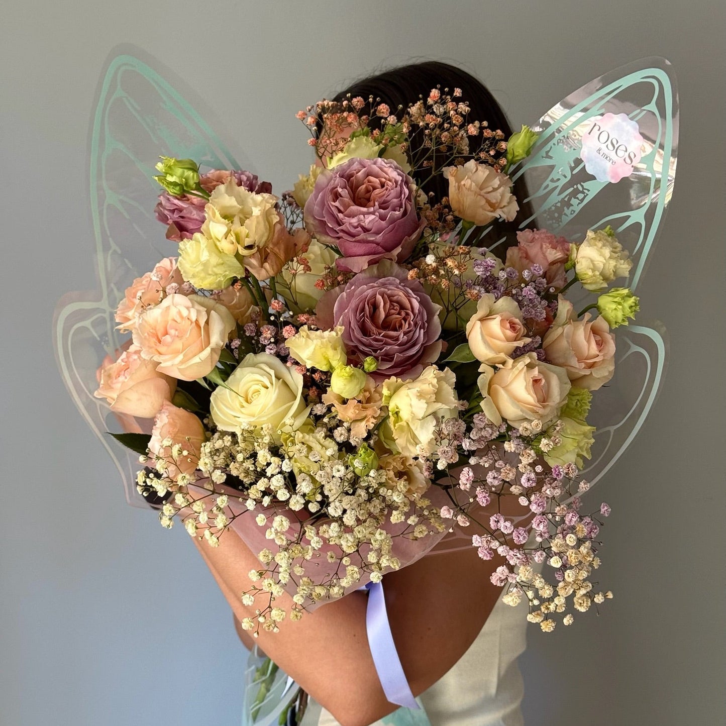 Bouquet of flowers held by a person with a butterfly-shaped frame.