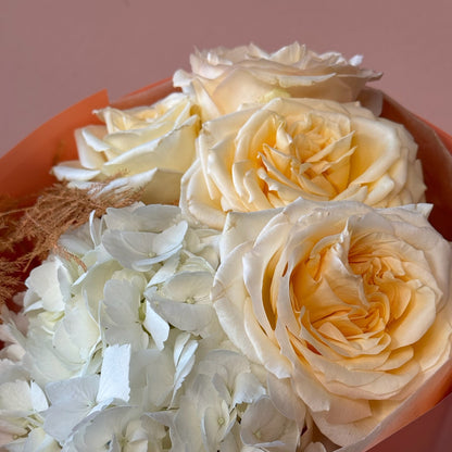 Bouquet of white and light yellow roses in a pink container.