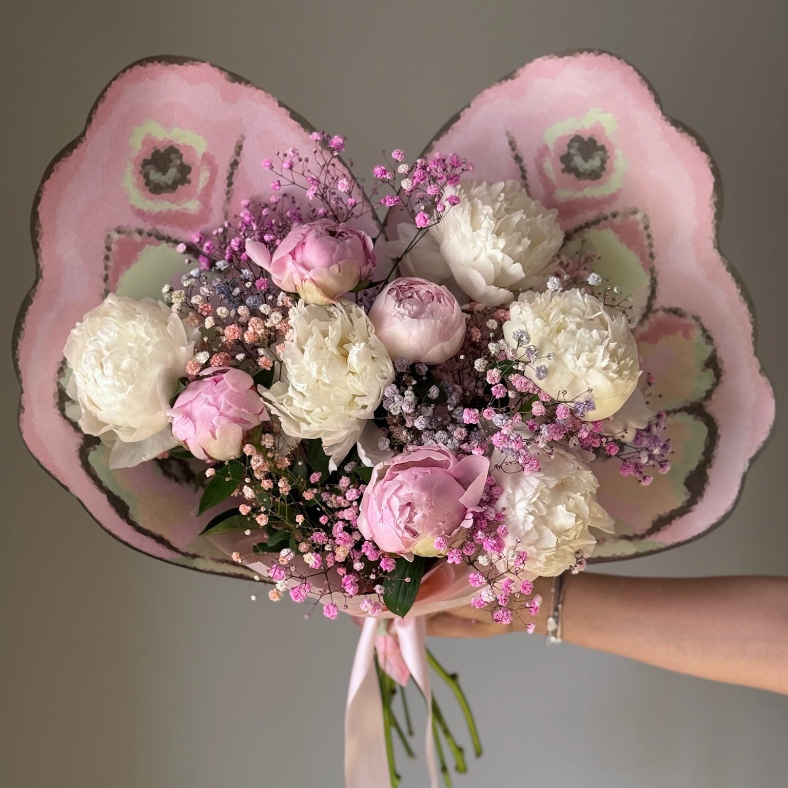White and pink flowers in butterfly bouquet held on grey background 