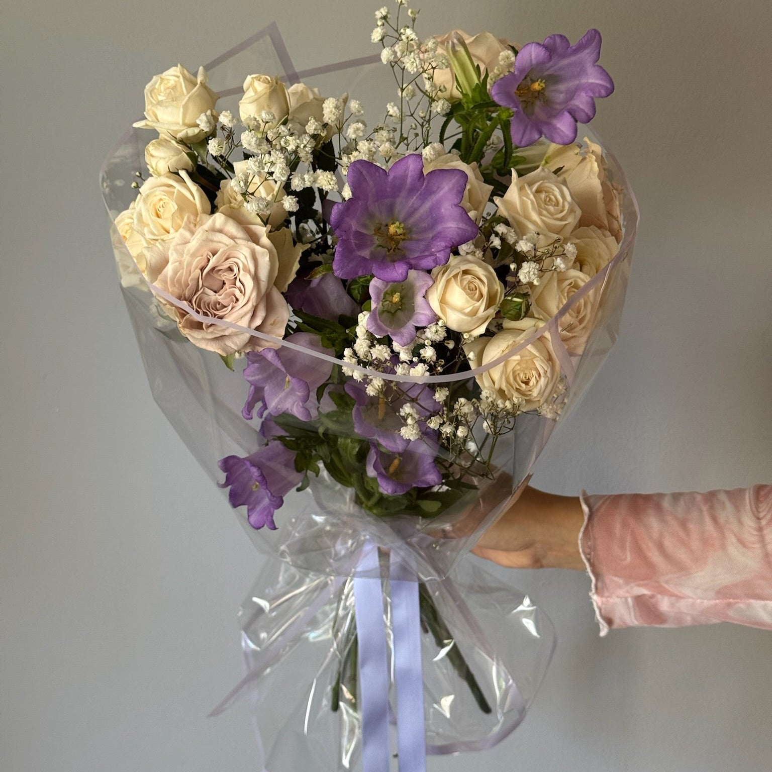 Buchet cu trandafiri albi gri si clopotei lila ambalat rotund