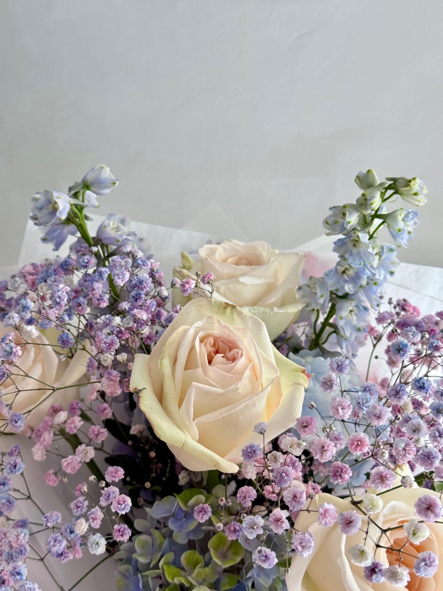 Bouquet of white and pastel-colored flowers on a light gray background