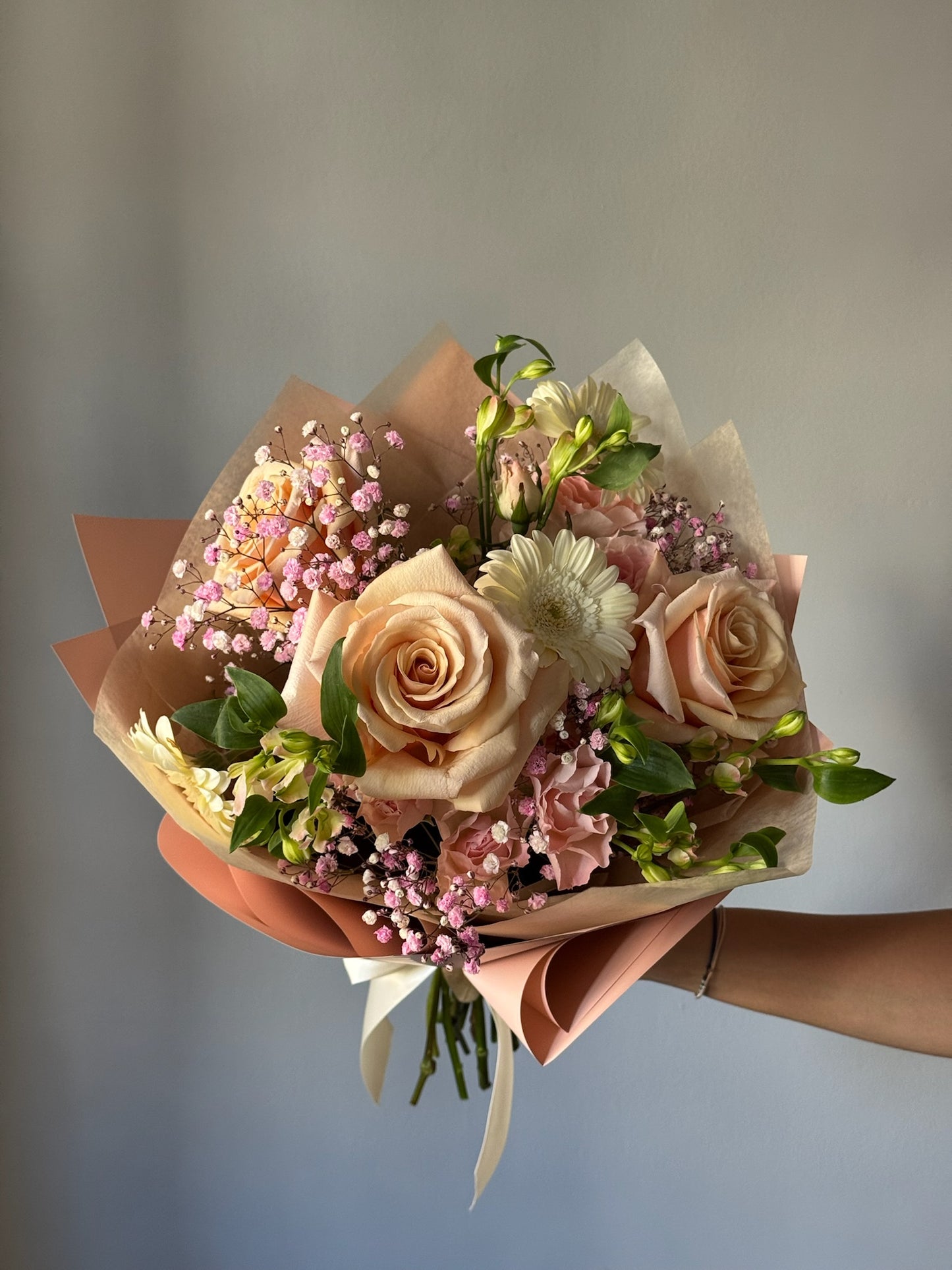 Bouquet of flowers held by a person against a neutral background