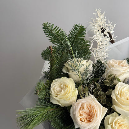 Bouquet of white and beige roses with greenery on a light gray background