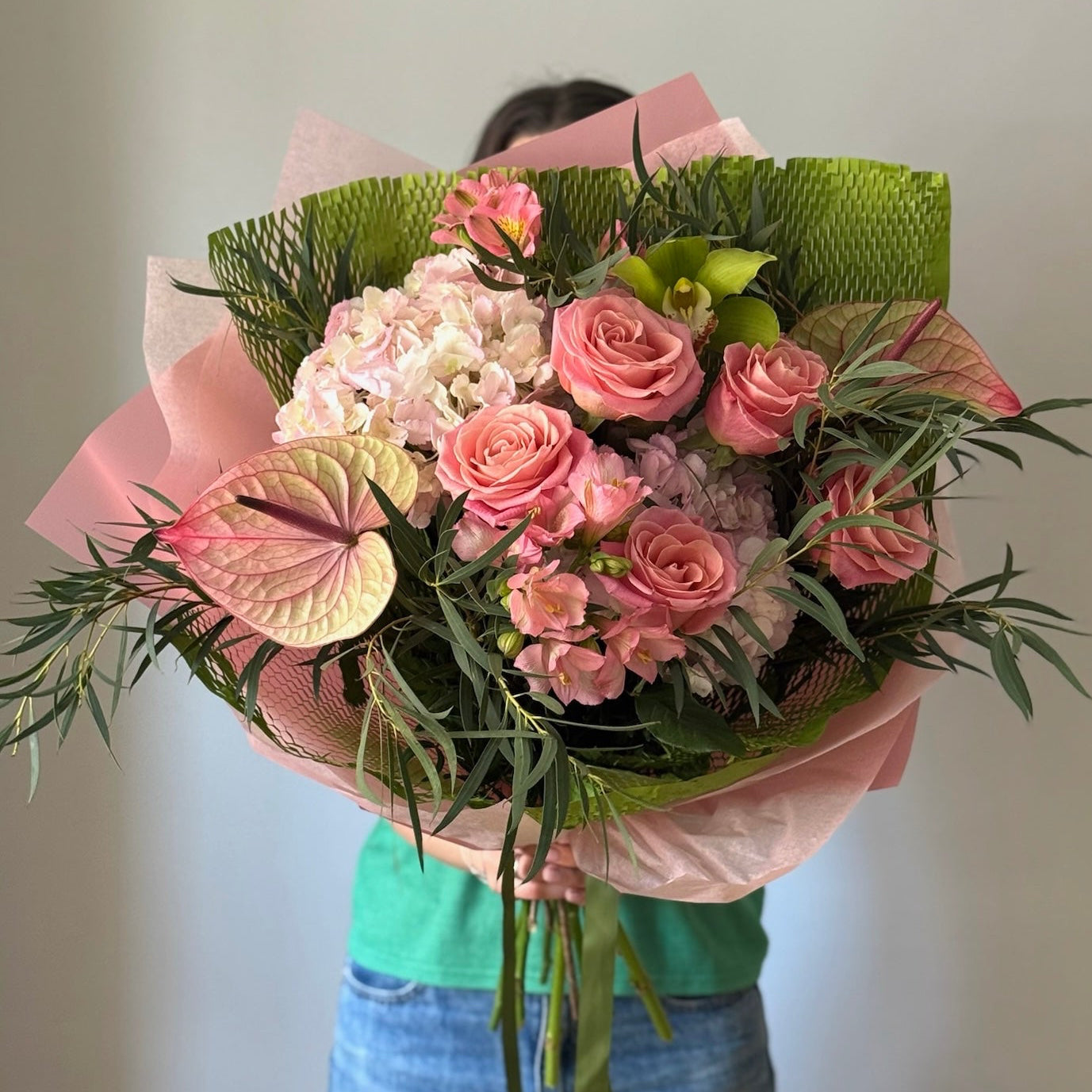 Big bouquet of pink flowers and greenery on grey background 