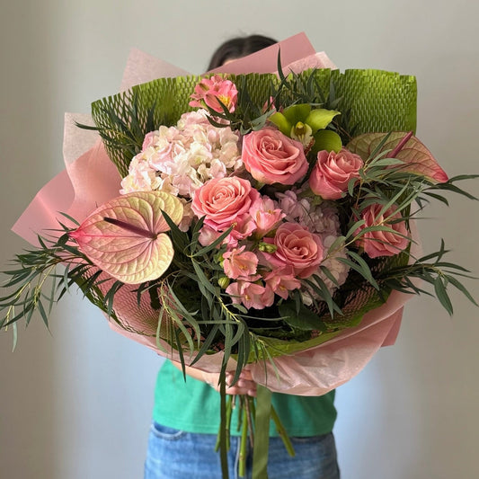 Big bouquet of pink flowers and greenery on grey background 