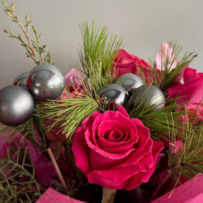 Bouquet of pink roses with greenery and silver ornaments on a neutral background