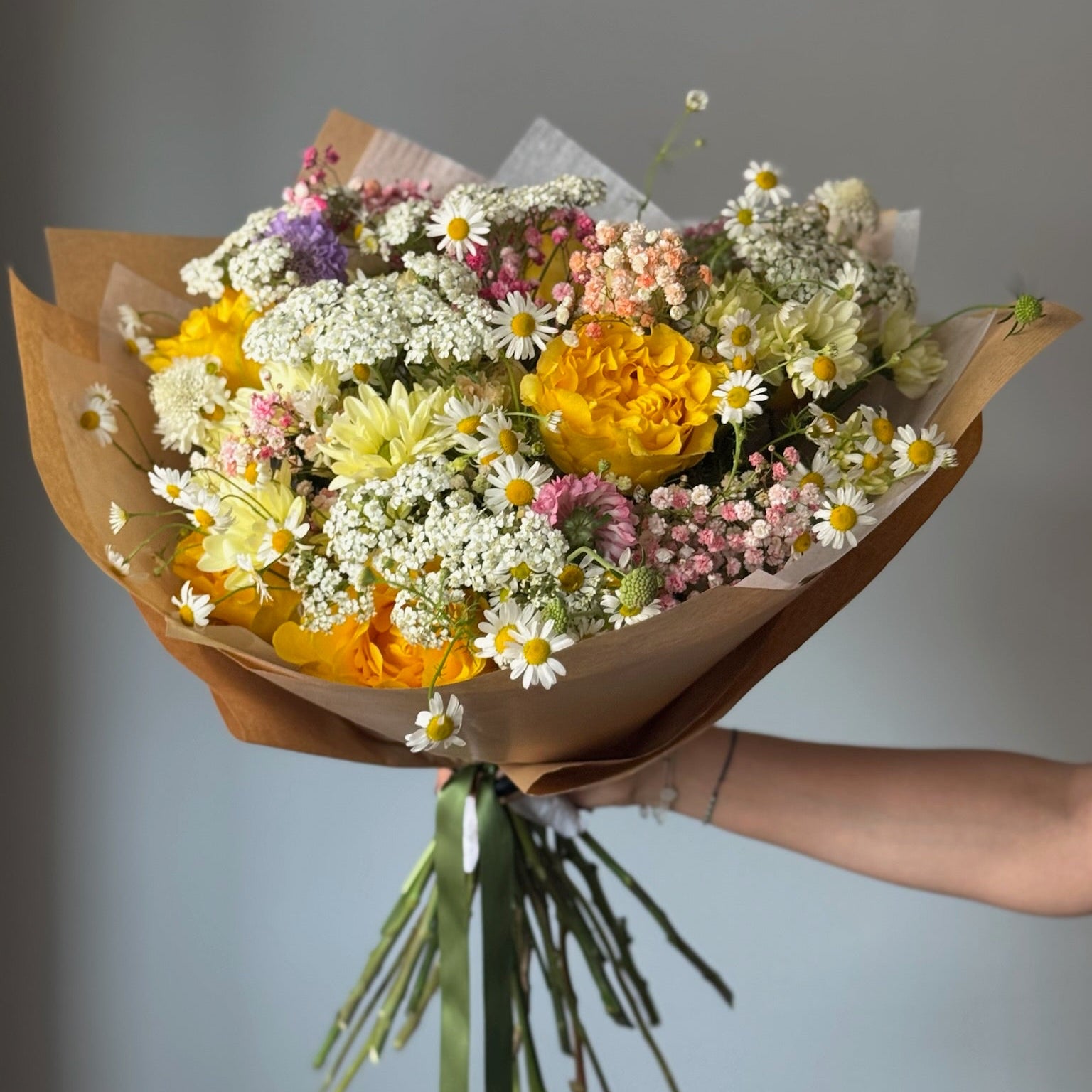 Buchet natural cu flori galbene și flori de câmp în ambalaj din hârtie kraft
