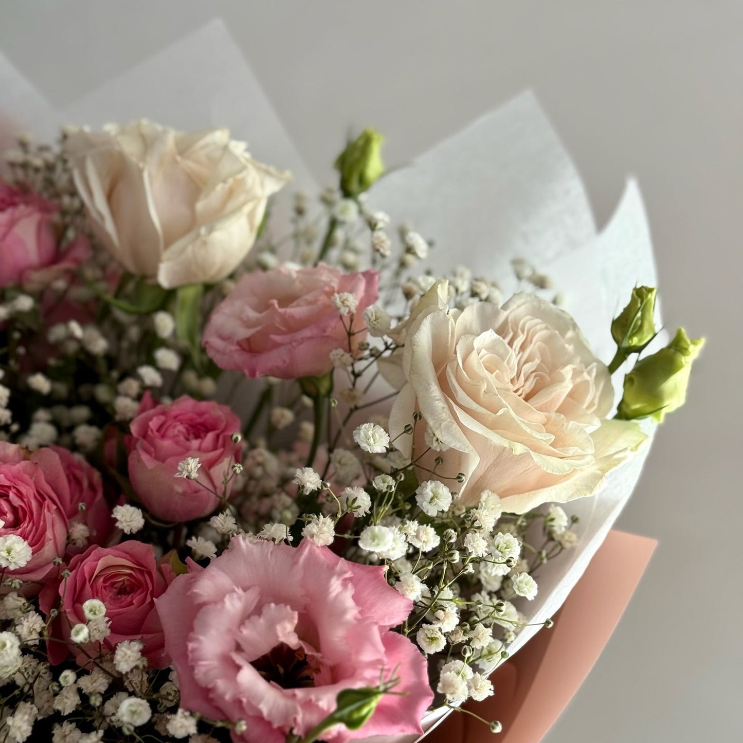 Bouquet of pink and white flowers with greenery on a light background