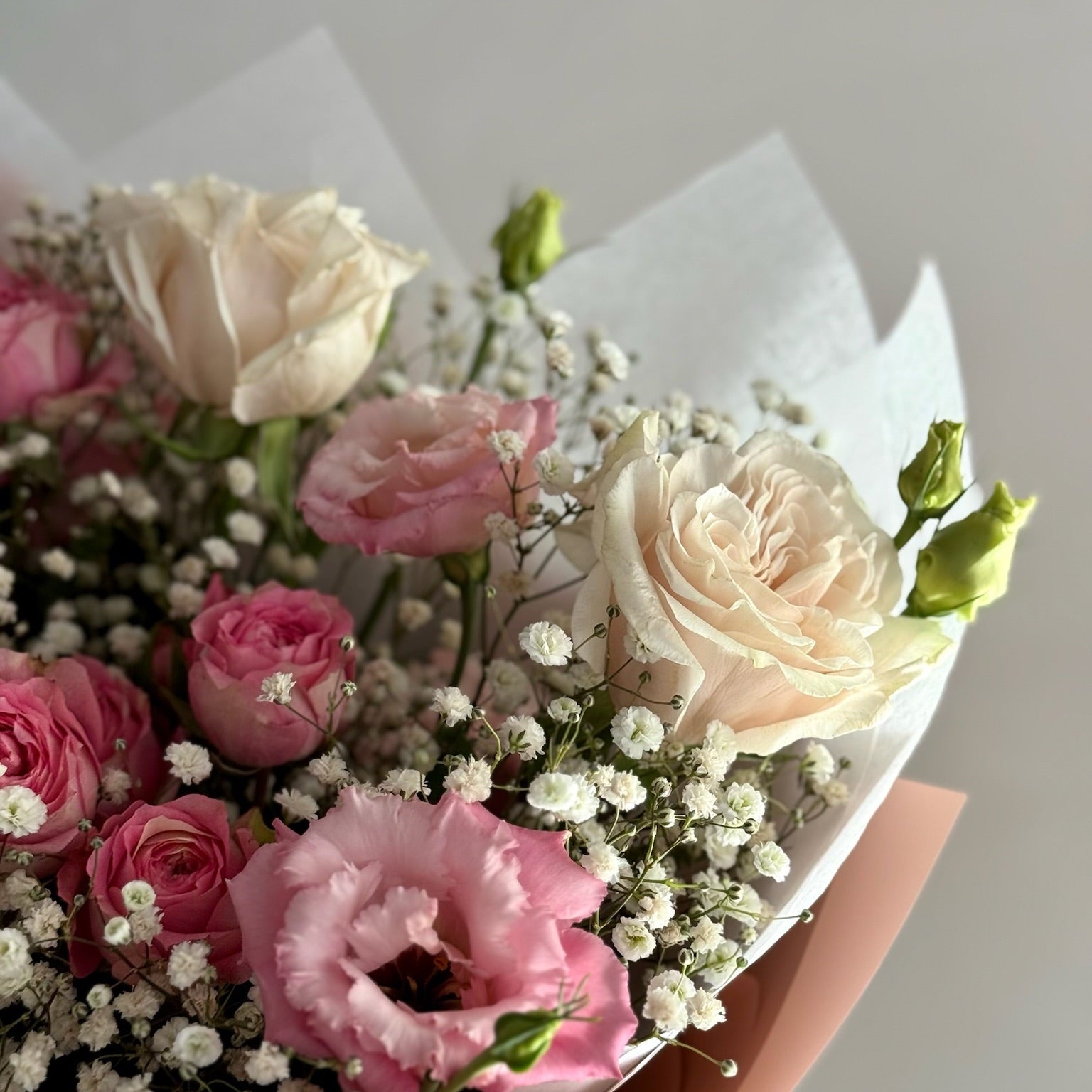 Bouquet of pink and white flowers with greenery on a light background