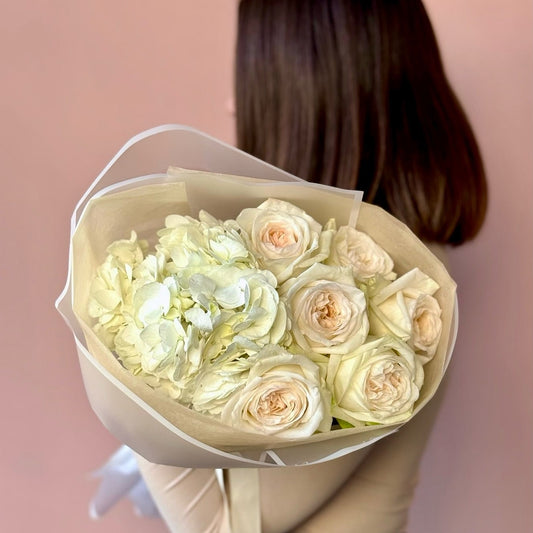 Bouquet of light-colored flowers held by a person with a blurred background