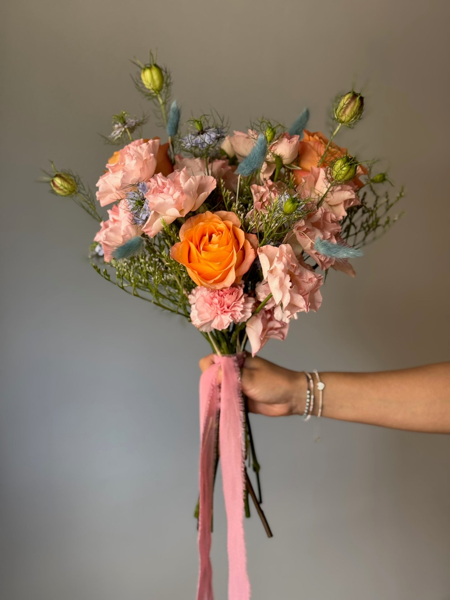 Colorful bouquet with flowers held on grey background 