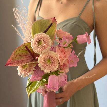 Bridal bouquet with green and pink flowers held by person 