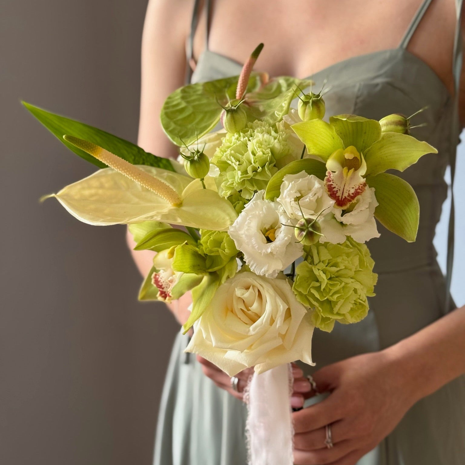 Green bridal bouquet with white and green flowers held by person