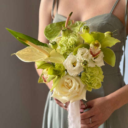Green bridal bouquet with white and green flowers held by person