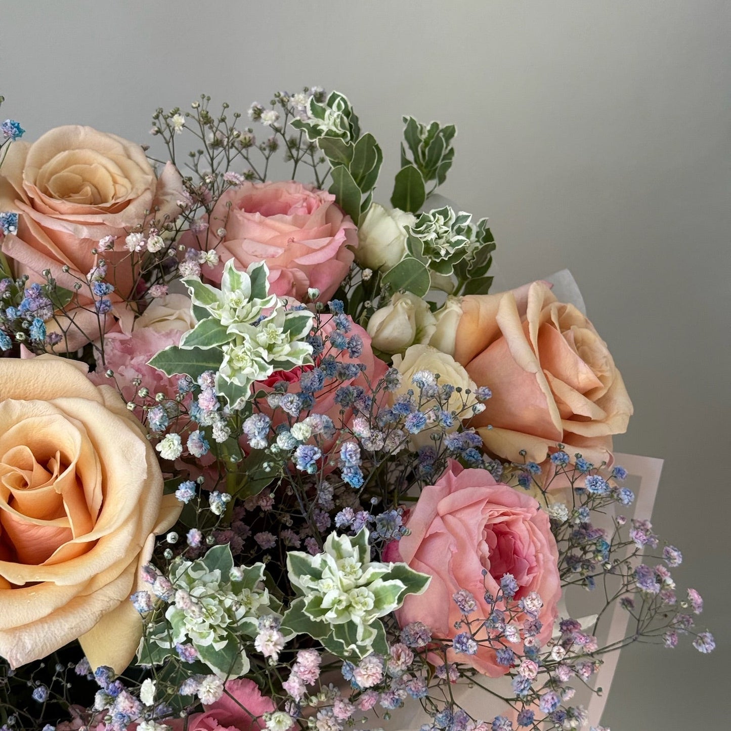 Bouquet of pink and peach roses with greenery on a gray background