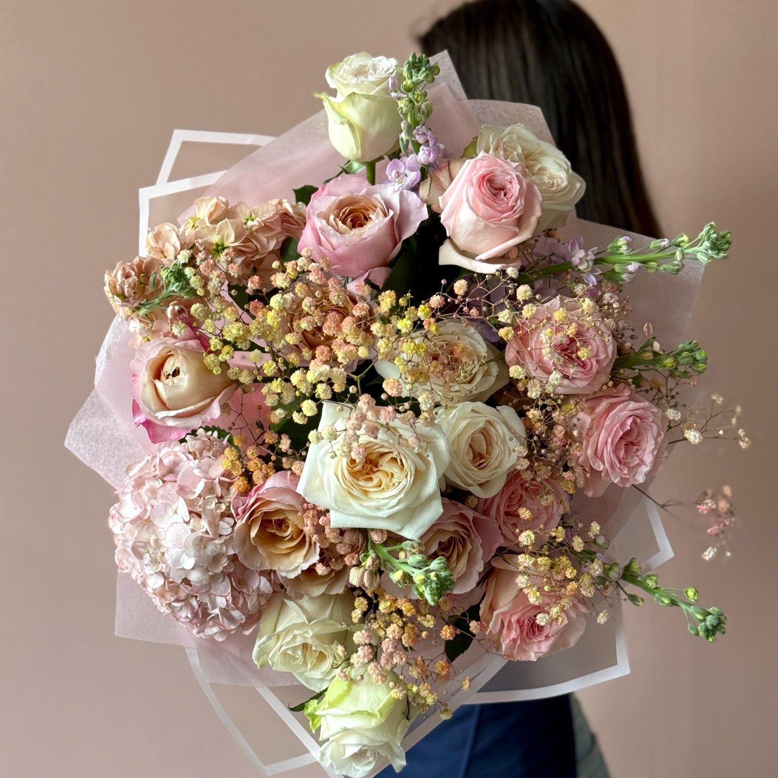Bouquet of flowers held by a person against a plain background