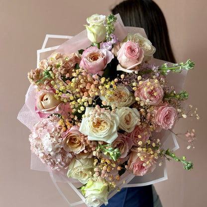 Bouquet of flowers held by a person against a plain background