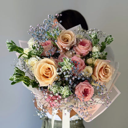 Buchet de flori ținut în mână pe fundal gri roses and more