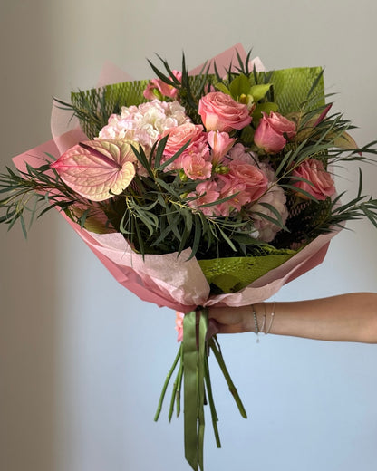 Bouquet of pink flowers with green wrapped on grey background 