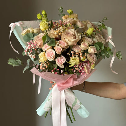 Flower bouquet with white and pink roses in wrapping paper on grey background 